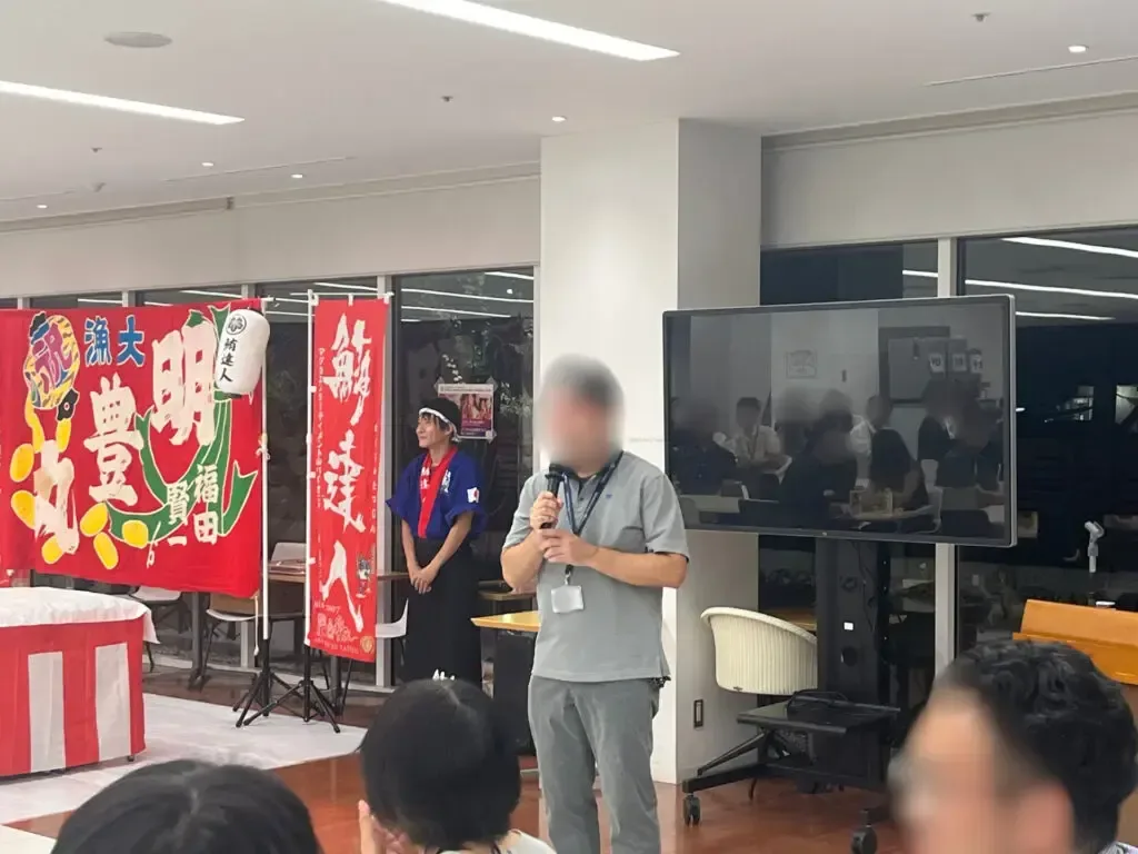 のぼりが並ぶ会場で開会の挨拶をする様子